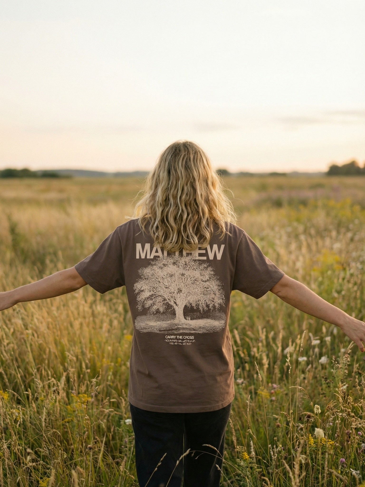 CTC approved original | pixels:6fa24ff8d79ed0b3c923e4d2643ef0a47c03bf305e32ddc6939d95e6544b2aef | Matthew 5:3 Tee | source:blonde_matthew-53-tee_field-arms-out.jpeg | side:back