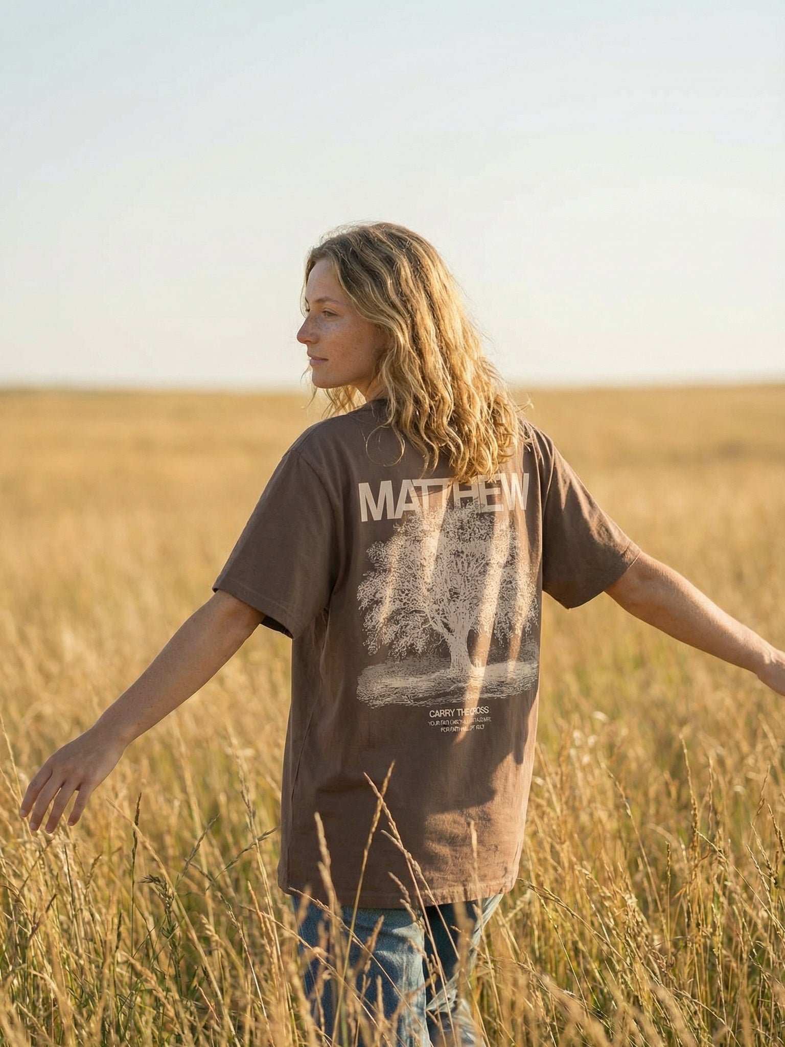 Woman wearing Matthew 5:3 Beatitudes tee in field back view - CarryTheCross