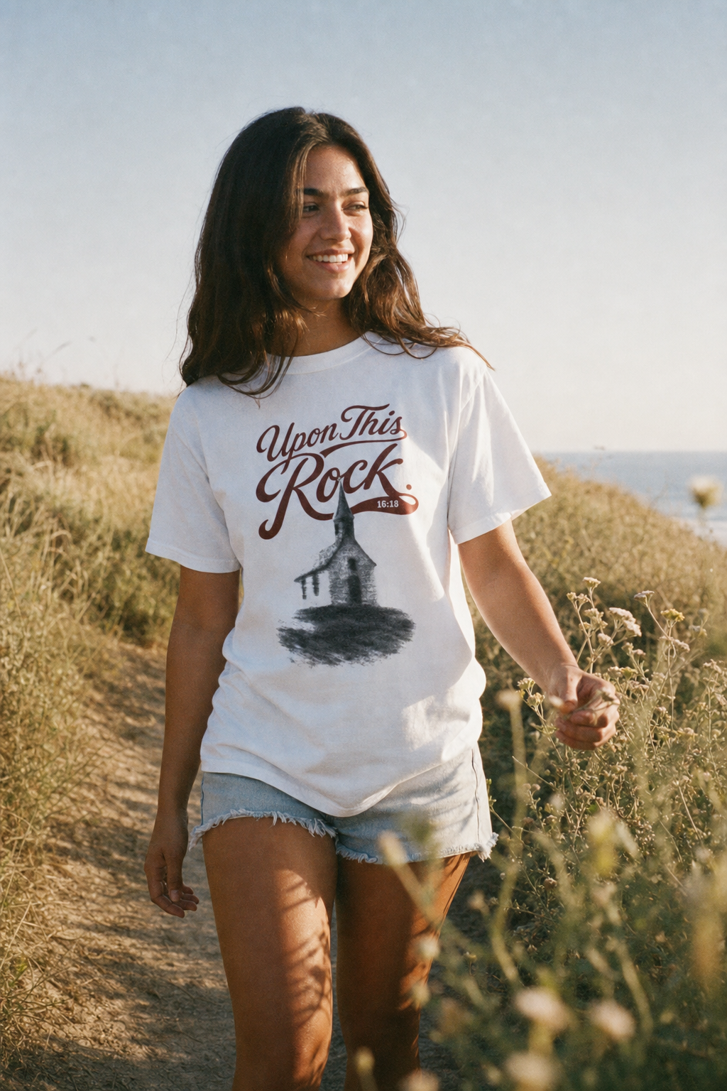 Woman wearing the white Upon This Rock Christian tee outdoors, featuring the Matthew 16:18 front design | CarryTheCross